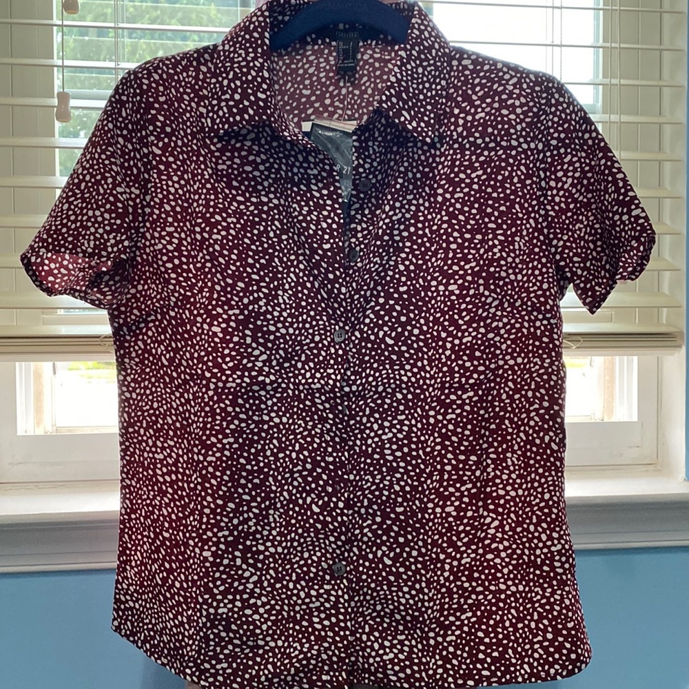This is a short sleeve shirt in burgundy with a white dotted design.